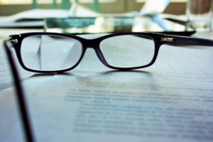 Eine Brille mit schwarzer Fassung liegt auf einem Dokument