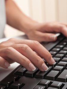 Frauenhände die auf einer schwarzen Tastatur schreiben