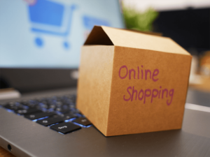 Eine kleine geöffnete Pappschachtel mit der Aufschrift "Online Shopping" steht auf einer Laptop-Tastatur