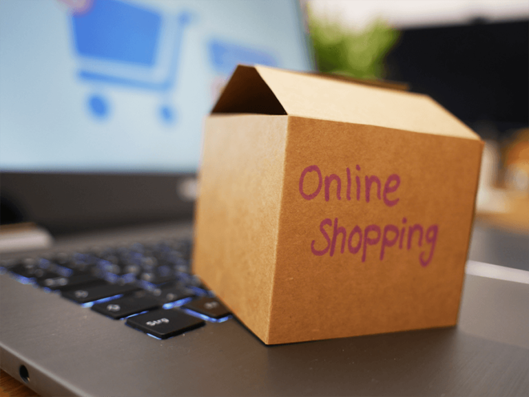Eine kleine geöffnete Pappschachtel mit der Aufschrift "Online Shopping" steht auf einer Laptop-Tastatur