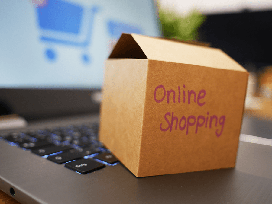 Eine kleine geöffnete Pappschachtel mit der Aufschrift "Online Shopping" steht auf einer Laptop-Tastatur