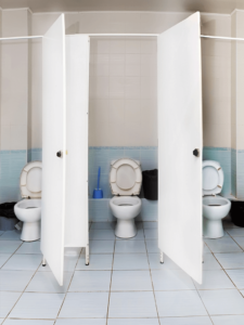 Öffentliche Sanitäranlage mit drei nebeneinanderliegenden offenen Toilettenkabinen